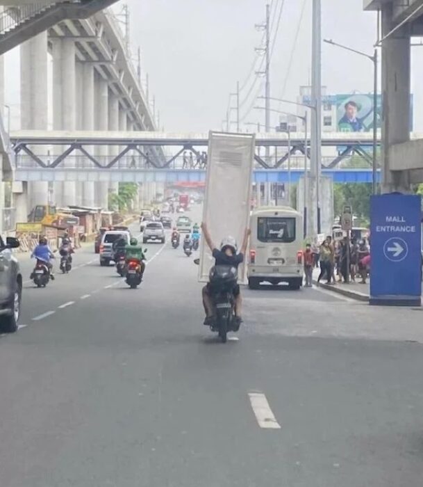 Motociclista cargando mueble mientras maneja