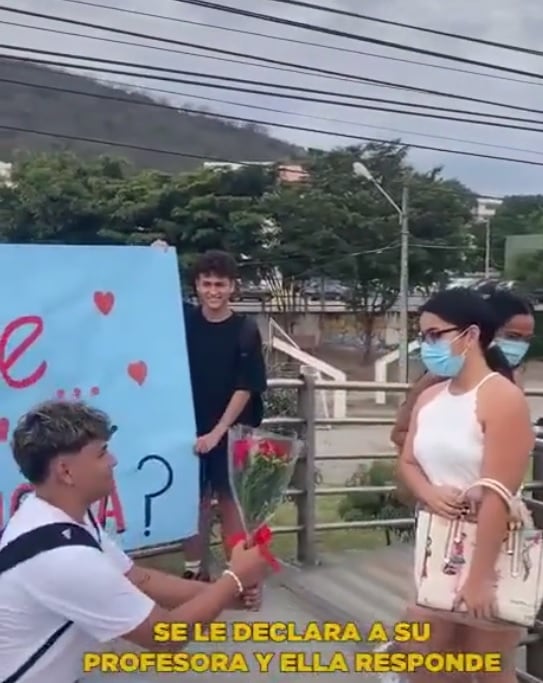Estudiante se le declara a su maestra frente a toda la escuela con cartulina y ramo de rosas