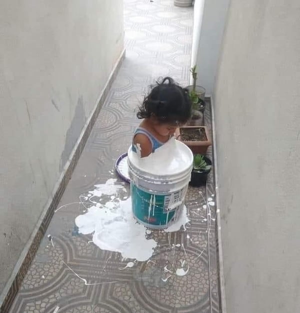 Niña metida en una cubeta de pintura