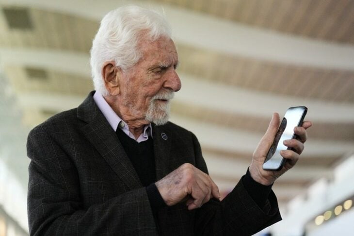 Martin Cooper observando con atención un celular